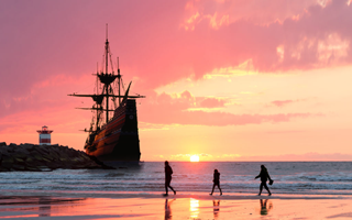 Tall Ship bij vuurtoren met zonsondergang